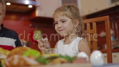 快乐的女孩和她的家人在同一张桌子上吃饭。 在家庆祝节日。 全家围桌吃饭